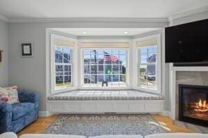 living area featuring crown molding and light hardwood / wood-style flooring