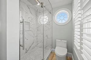 bathroom featuring a shower with door, wood-type flooring, and toilet