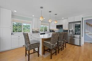 kitchen featuring stainless steel fridge with ice dispenser, a center island, white cabinets, and decorative light fixtures