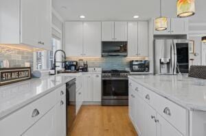 kitchen with decorative backsplash, stainless steel appliances, extractor fan, pendant lighting, and white cabinets