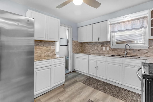 kitchen featuring appliances with stainless steel finishes, light stone countertops, sink, and white cabinets