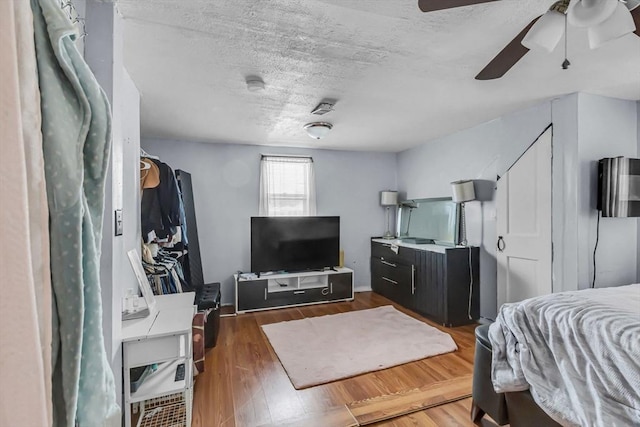 bedroom with ceiling fan, dark hardwood / wood-style floors, and a textured ceiling