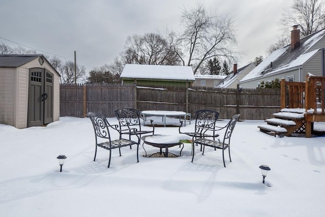 yard layered in snow featuring a storage unit