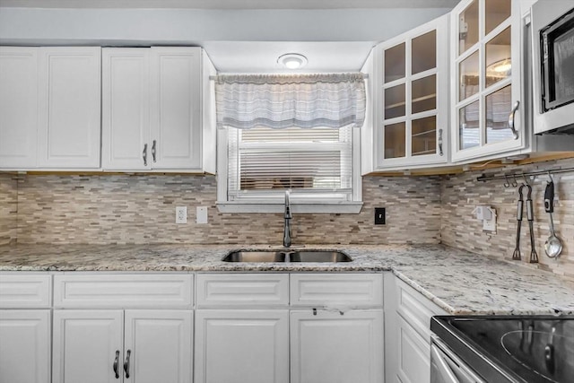 kitchen featuring sink, stainless steel microwave, white cabinets, and decorative backsplash