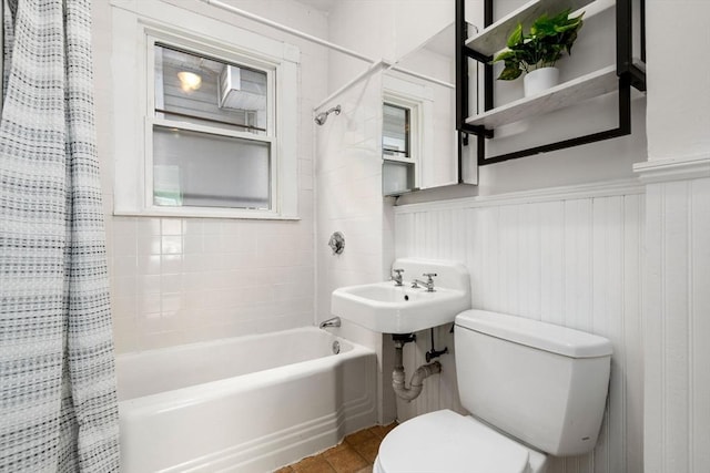 bathroom featuring tile patterned floors, a wainscoted wall, toilet, and shower / bathtub combination with curtain