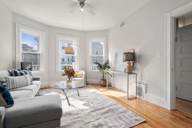 living area with visible vents, baseboards, ceiling fan, and hardwood / wood-style flooring