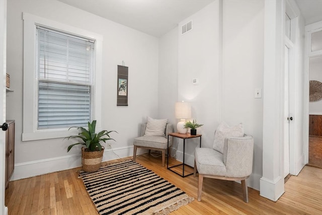 sitting room featuring visible vents, baseboards, and wood finished floors