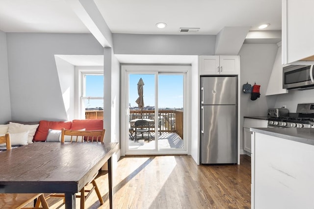 kitchen featuring appliances with stainless steel finishes, white cabinetry, and hardwood / wood-style flooring