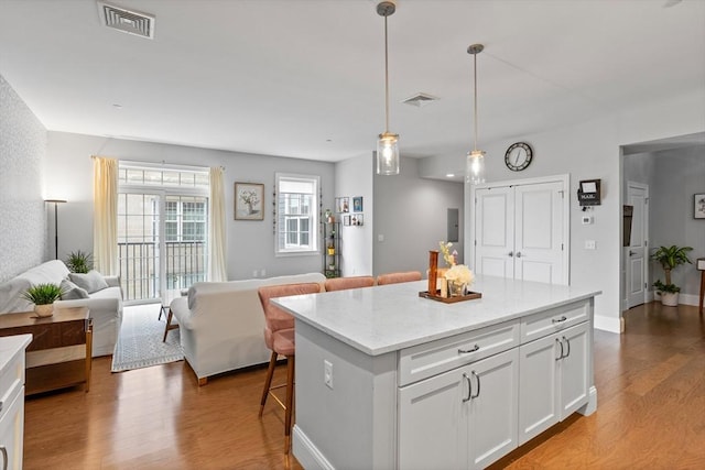 8 Sanborn St Unit 2012, Reading, MA 01867 - kitchen with wood finished floors, open floor plan, a kitchen breakfast bar, white cabinetry, and a kitchen island