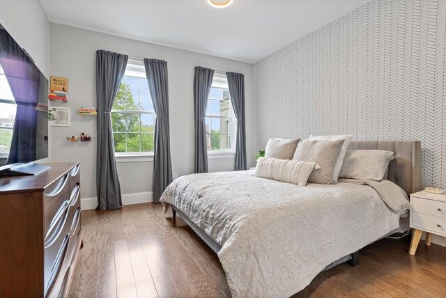 8 Sanborn St Unit 2012, Reading, MA 01867 - bedroom with an accent wall, wallpapered walls, baseboards, and wood finished floors