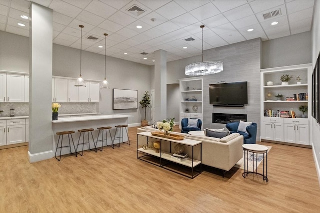 8 Sanborn St Unit 2012, Reading, MA 01867 - living area featuring a high ceiling, a drop ceiling, light wood-style floors, a large fireplace, and built in shelves