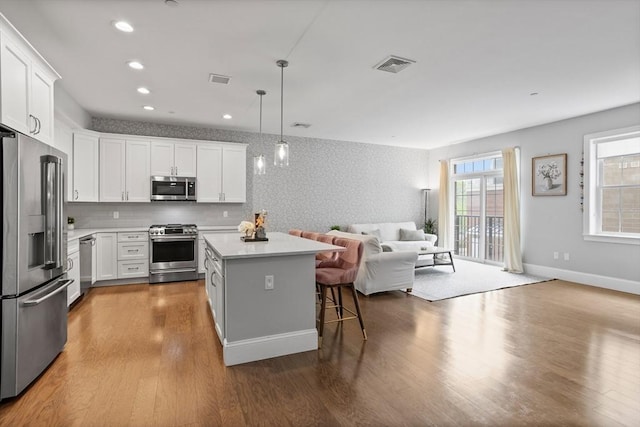 8 Sanborn St Unit 2012, Reading, MA 01867 - kitchen featuring appliances with stainless steel finishes, open floor plan, a kitchen island, light countertops, and wood finished floors