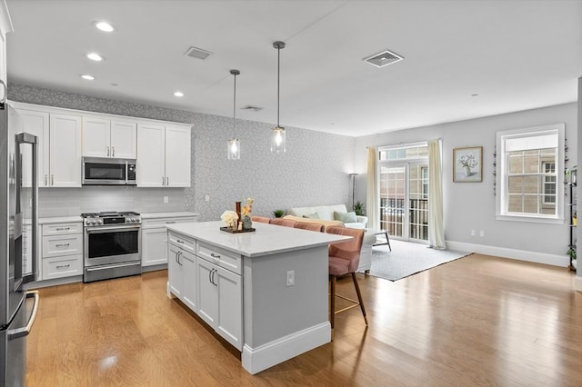 8 Sanborn St Unit 2012, Reading, MA 01867 - kitchen featuring appliances with stainless steel finishes, open floor plan, light wood-style flooring, a kitchen island, and wallpapered walls