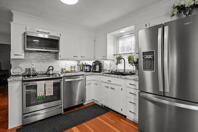 kitchen featuring crown molding, a sink, wood finished floors, and stainless steel appliances