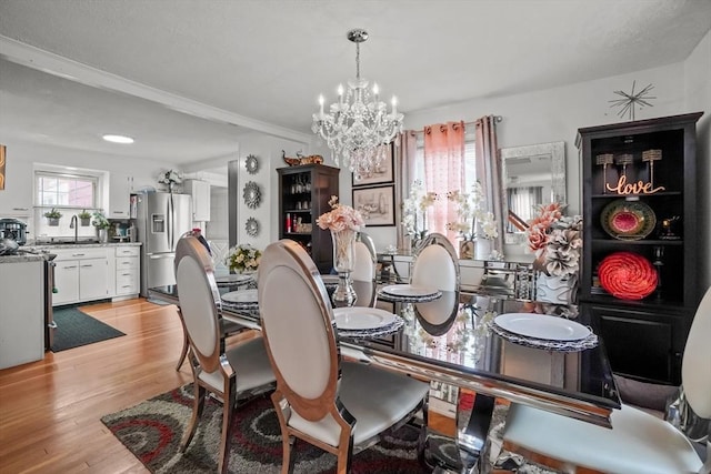 dining space featuring an inviting chandelier, ornamental molding, and light wood-style flooring