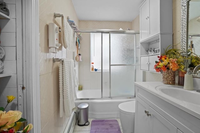 bathroom with tile patterned flooring, vanity, tile walls, combined bath / shower with glass door, and a baseboard heating unit