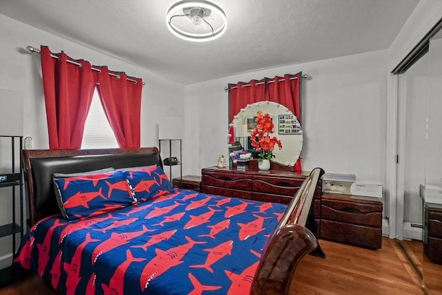bedroom with baseboard heating and wood finished floors