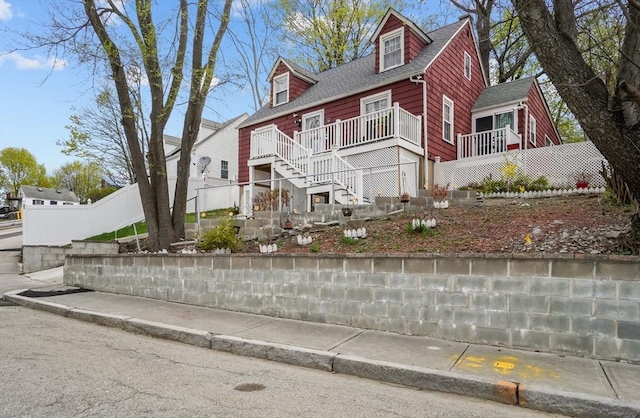 view of property exterior with fence, a shingled roof, and stairs