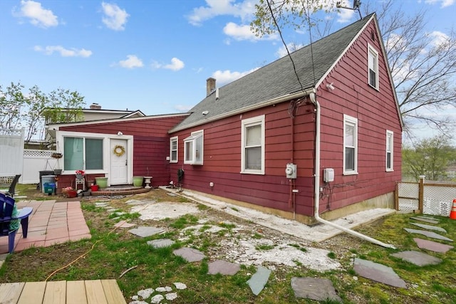 rear view of house featuring a patio, fence, and a chimney