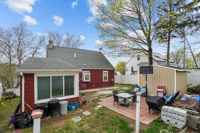 back of house with a chimney, an outbuilding, a patio area, fence, and a storage unit