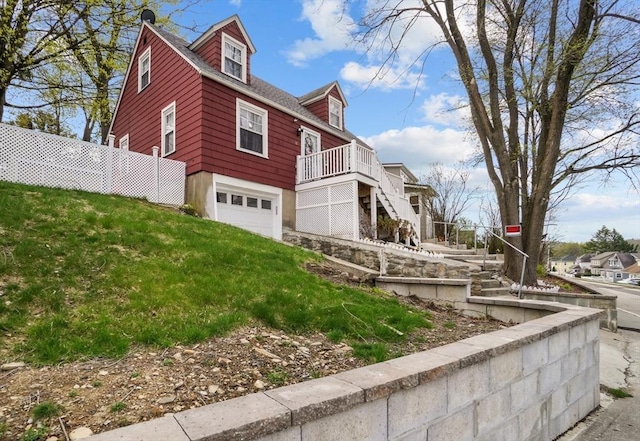 view of property exterior with an attached garage, stairway, and a deck