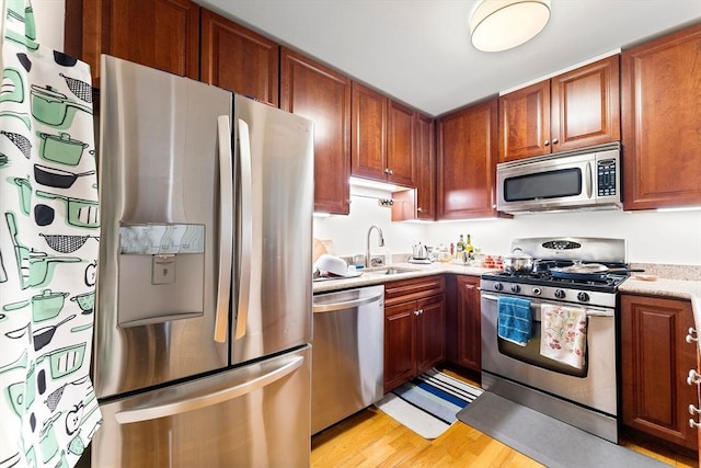 318 Rindge Ave Unit 411, Cambridge, MA 02140 - kitchen featuring stainless steel appliances, light wood-style flooring, and brown cabinetry