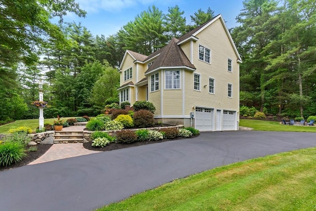 15 Hillside St, Rowley, MA 01969 - view of side of home featuring asphalt driveway, a garage, view of wooded area, and a yard