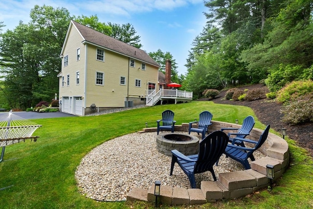 15 Hillside St, Rowley, MA 01969 - rear view of house with an outdoor fire pit, a garage, a deck, a lawn, and asphalt driveway