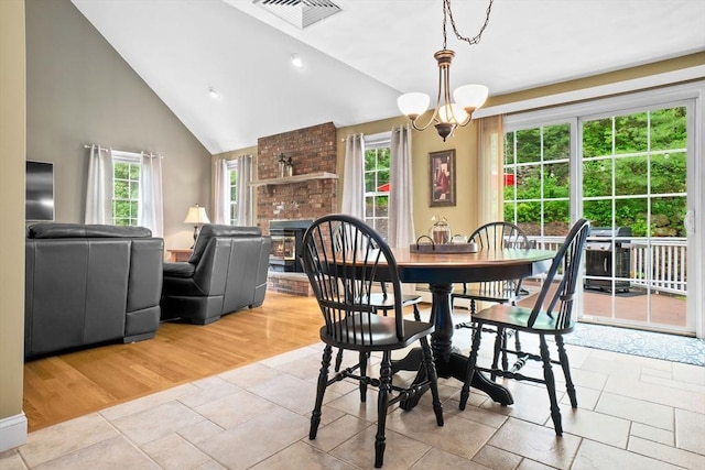 15 Hillside St, Rowley, MA 01969 - dining area with a brick fireplace, high vaulted ceiling, a chandelier, and light wood-style flooring