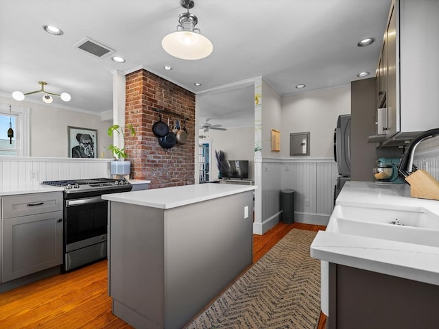 5 Tremont St Unit 3, Cambridge, MA 02139 - kitchen with stainless steel gas range oven, a sink, gray cabinets, crown molding, and light wood-type flooring