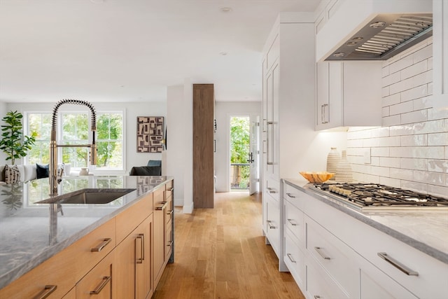 kitchen featuring white cabinets, plenty of natural light, and wall chimney range hood