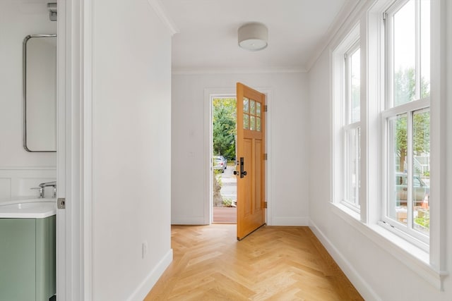 foyer with light parquet flooring, ornamental molding, and sink