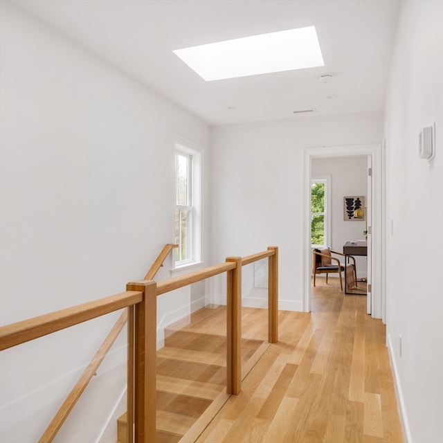 corridor with a skylight and light hardwood / wood-style flooring