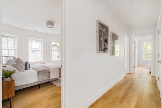 hall with light hardwood / wood-style floors and a healthy amount of sunlight