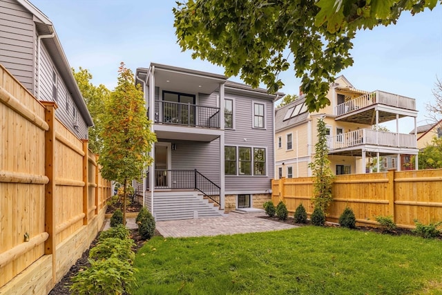 rear view of house featuring a balcony and a yard