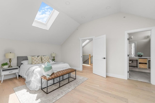 bedroom with connected bathroom, light hardwood / wood-style floors, and lofted ceiling with skylight