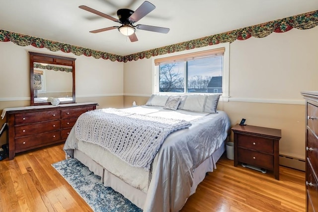 bedroom with baseboard heating, light wood finished floors, and ceiling fan