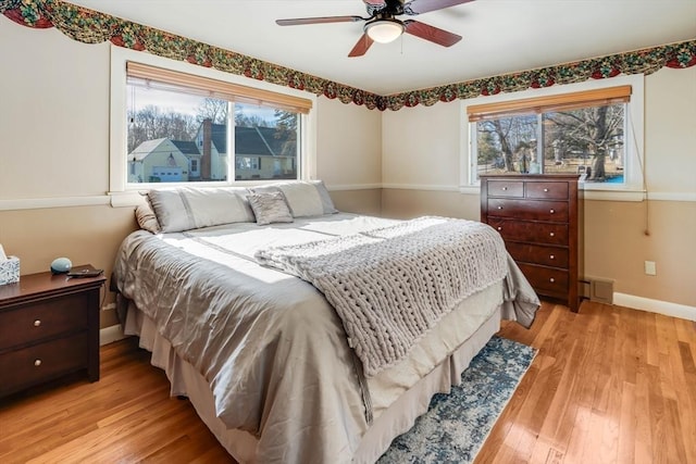 bedroom featuring baseboards, multiple windows, light wood-style flooring, and a ceiling fan