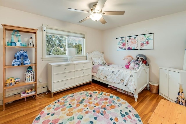 bedroom featuring a ceiling fan, light wood-type flooring, and baseboard heating