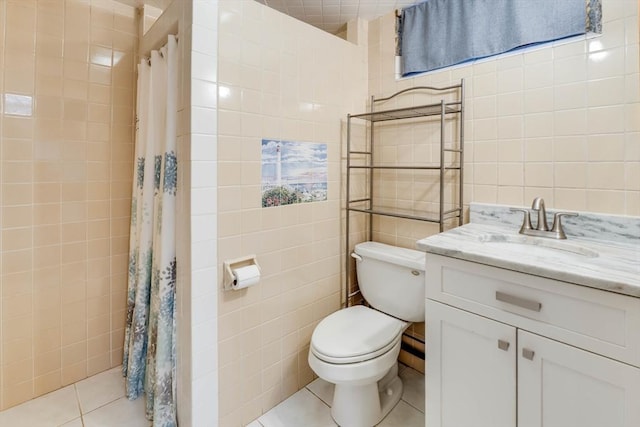 full bath with tile patterned floors, toilet, a tile shower, tile walls, and vanity