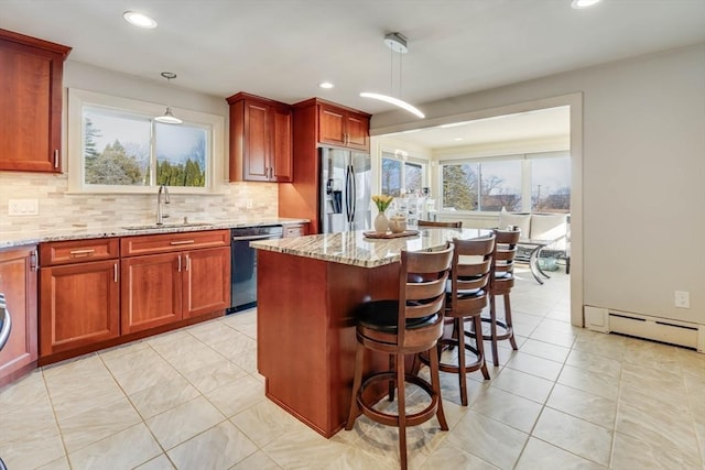 kitchen with light stone countertops, dishwasher, baseboard heating, stainless steel fridge, and a sink