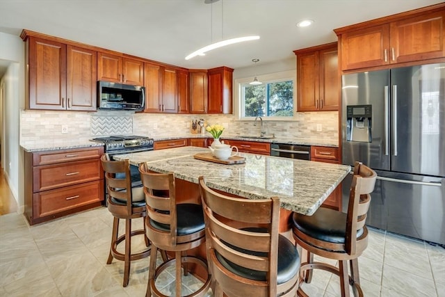 kitchen featuring a sink, a center island, light stone countertops, and stainless steel appliances