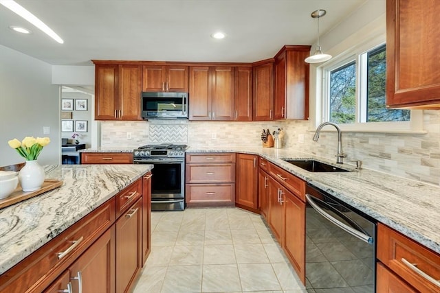 kitchen featuring light stone countertops, a sink, decorative backsplash, hanging light fixtures, and appliances with stainless steel finishes