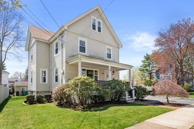 american foursquare style home featuring a porch and a front lawn