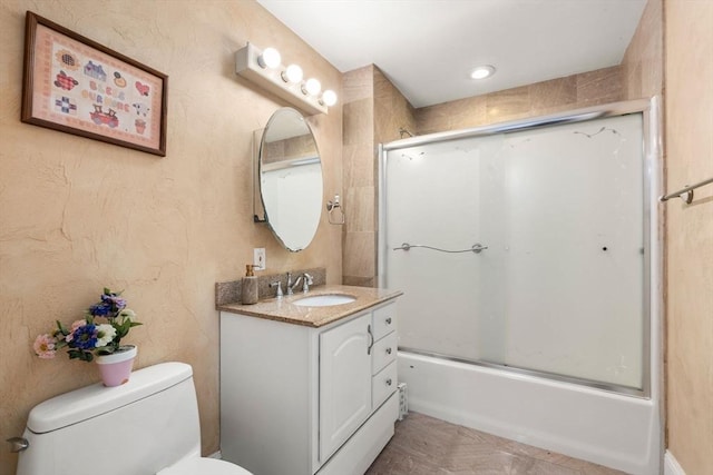 bathroom featuring toilet, bath / shower combo with glass door, and vanity