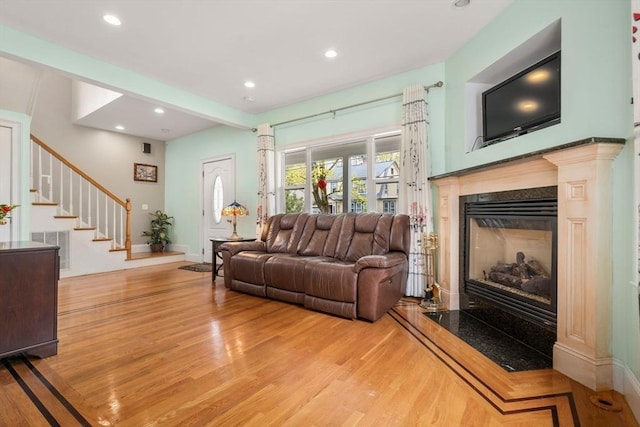 living room with recessed lighting, a high end fireplace, wood finished floors, and stairway