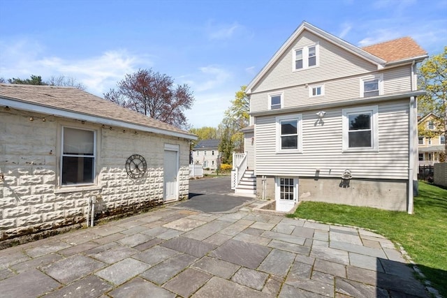 rear view of house with a shingled roof and a patio area