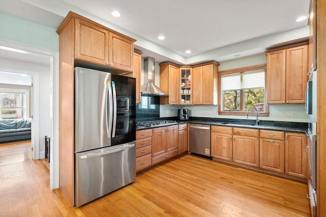 kitchen featuring light wood-type flooring, a sink, stainless steel appliances, recessed lighting, and wall chimney exhaust hood