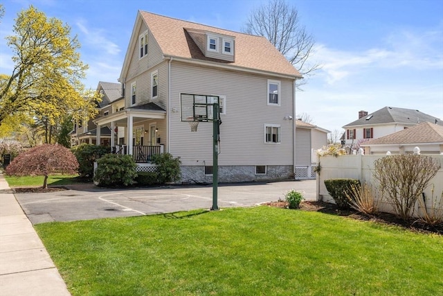 view of home's exterior with a lawn, fence, and roof with shingles