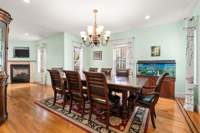 dining room with an inviting chandelier, recessed lighting, a fireplace, and light wood finished floors